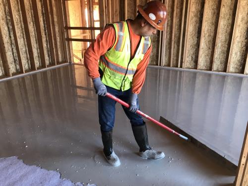 Insul-Flow employee applys gypsum flooring over sound matting underlayment